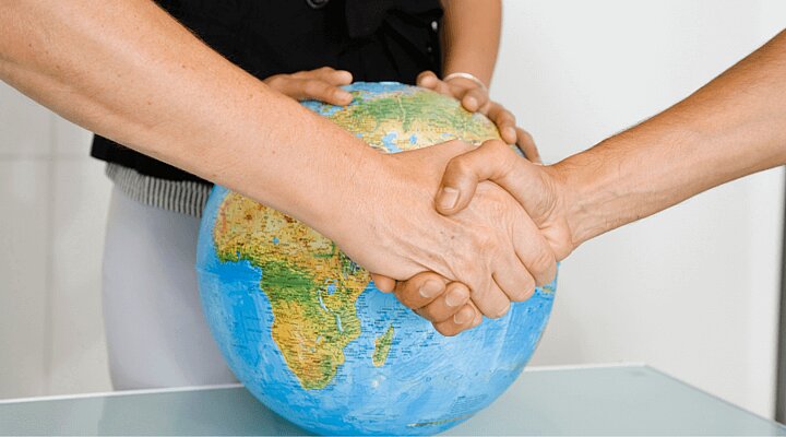 Grafika dekoracyjna. Uścisk dłoni, w tle globus.