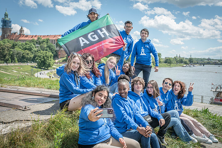 Grupa studentów pozująca do zdjęcia z flagą AGH.